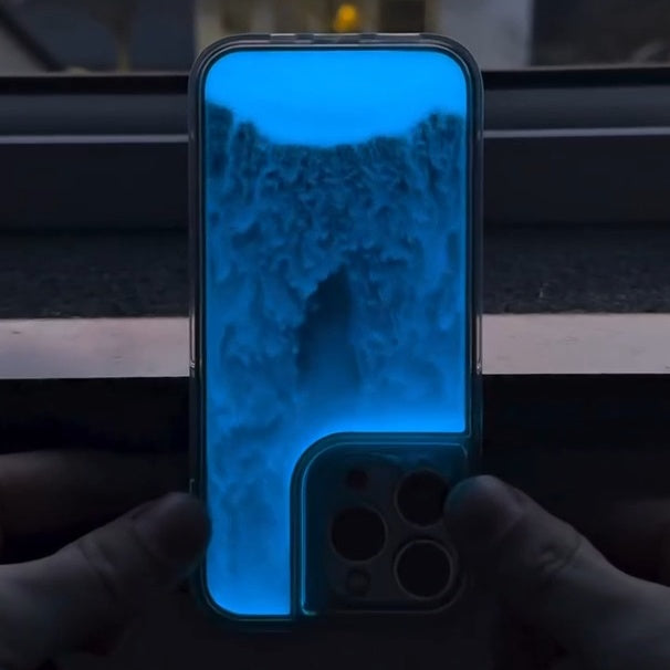 Phone with blue screen held by hands in a dark setting